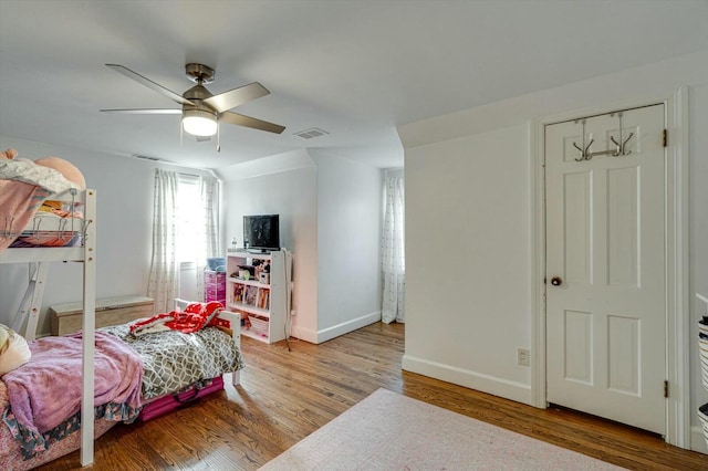 bedroom featuring a ceiling fan, wood finished floors, visible vents, and baseboards