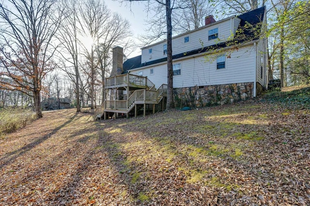 back of property with a deck, stairs, and a chimney