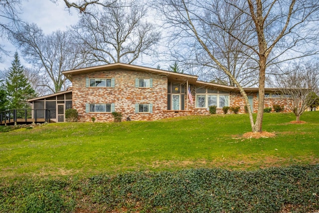 view of front of property with a front lawn, brick siding, and a sunroom