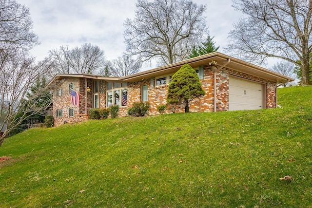 view of front of house featuring brick siding, an attached garage, and a front yard