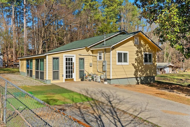 rear view of house featuring a shingled roof and fence