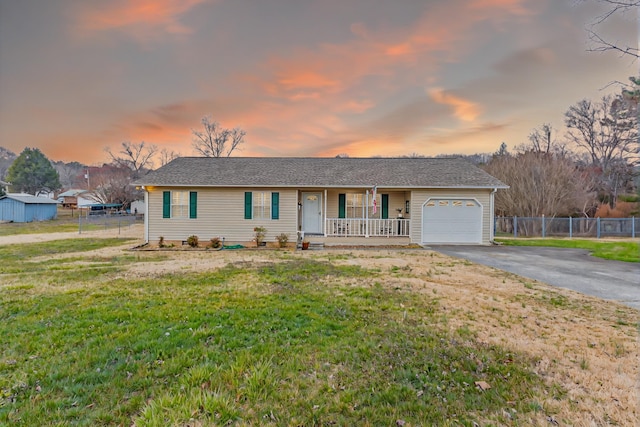 single story home featuring aphalt driveway, fence, a yard, covered porch, and a garage