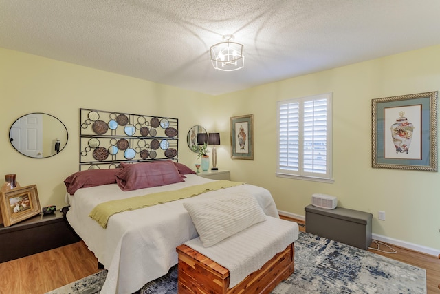 bedroom with wood finished floors, baseboards, and a textured ceiling