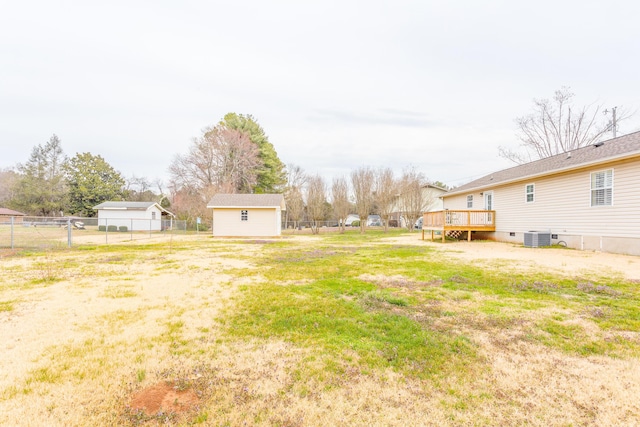 view of yard featuring fence, central air condition unit, a wooden deck, an outdoor structure, and a storage unit