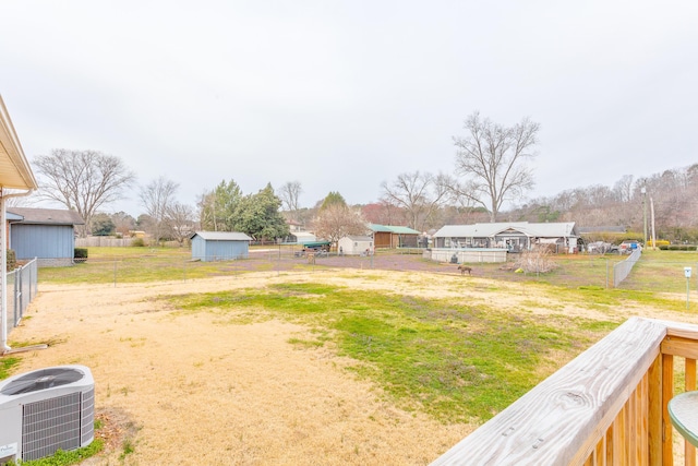 view of yard with a storage unit, an outdoor structure, central AC, and fence