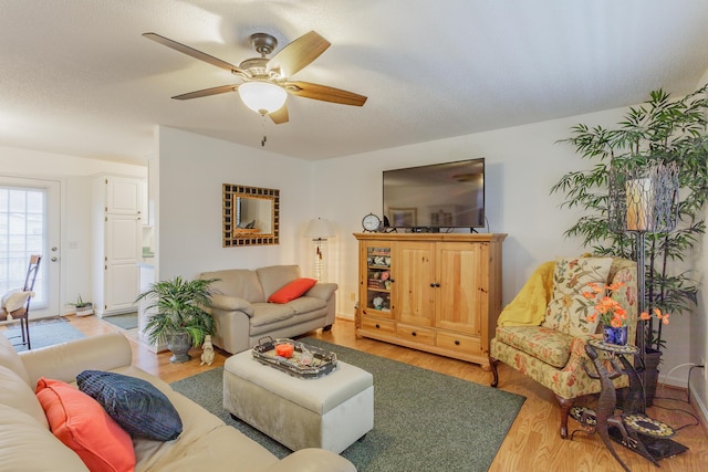 living room with a textured ceiling, light wood-type flooring, and a ceiling fan