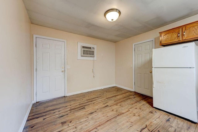 kitchen with brown cabinetry, light wood-style floors, freestanding refrigerator, and a wall mounted AC