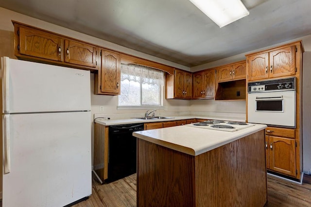 kitchen featuring a sink, dark wood-style floors, white appliances, brown cabinetry, and light countertops