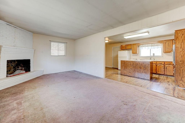 unfurnished living room with light colored carpet, a fireplace, and light wood-type flooring