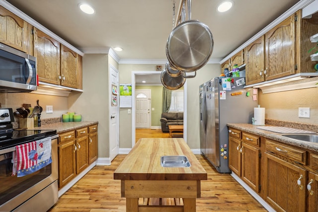 kitchen with butcher block countertops, light wood-style flooring, recessed lighting, stainless steel appliances, and crown molding