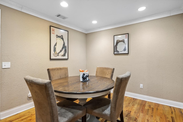 dining space featuring crown molding, wood finished floors, visible vents, and baseboards