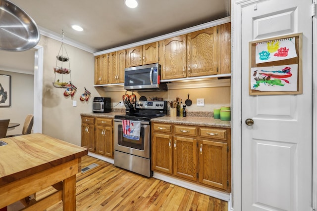 kitchen featuring light wood finished floors, visible vents, light countertops, appliances with stainless steel finishes, and brown cabinetry