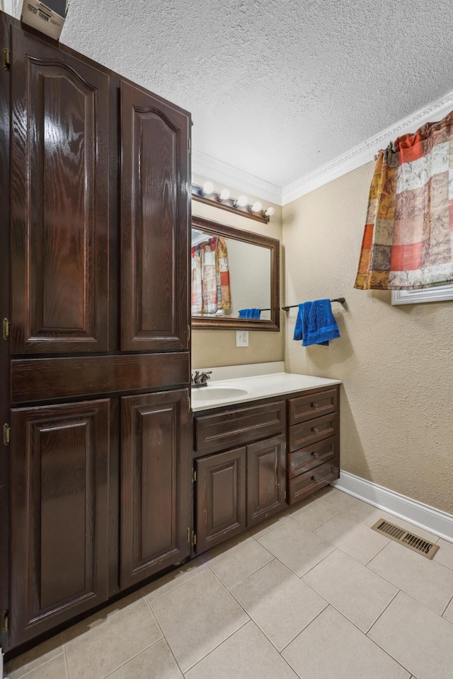 bathroom with tile patterned floors, a textured ceiling, baseboards, and ornamental molding