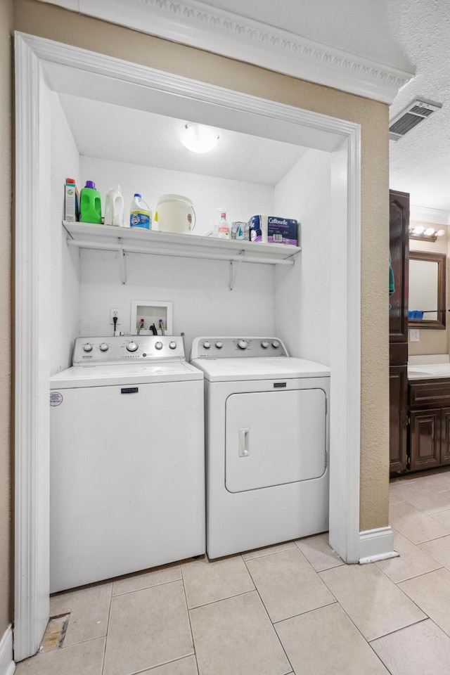 clothes washing area featuring light tile patterned floors, visible vents, a textured ceiling, and independent washer and dryer