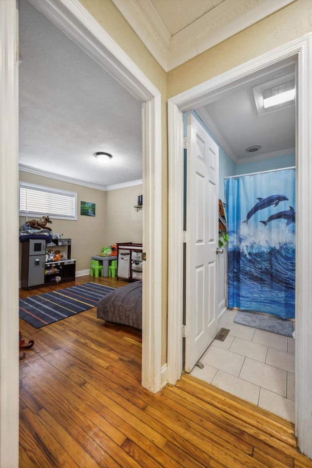 hall featuring a textured ceiling, crown molding, and hardwood / wood-style flooring