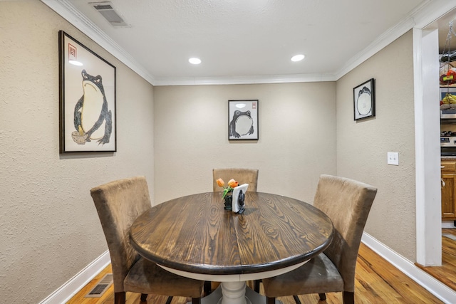 dining space featuring visible vents, wood finished floors, and ornamental molding