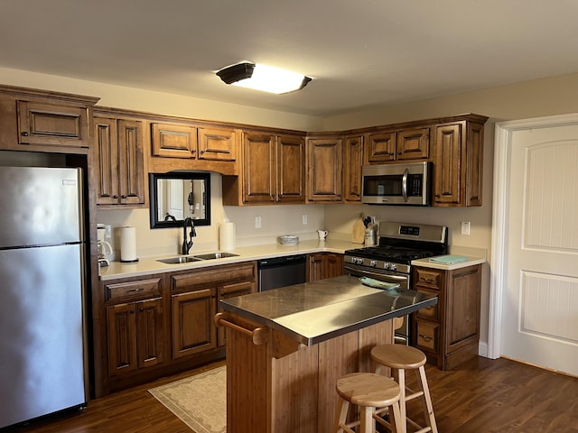 kitchen with a kitchen bar, a sink, a center island, appliances with stainless steel finishes, and dark wood-style flooring