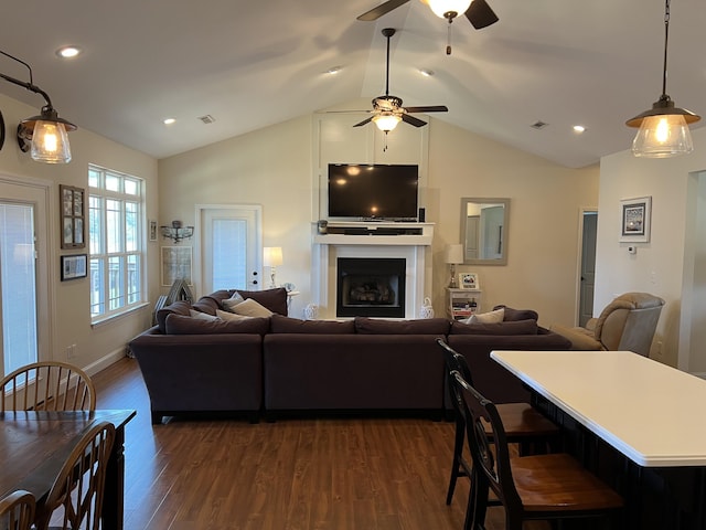 living area with dark wood finished floors, a fireplace, lofted ceiling, and a ceiling fan