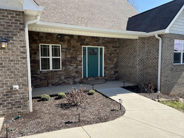 view of exterior entry with stone siding and roof with shingles