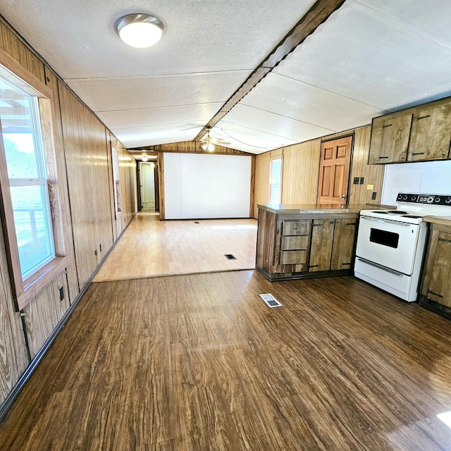 kitchen featuring dark wood finished floors, wood walls, lofted ceiling with beams, and electric stove