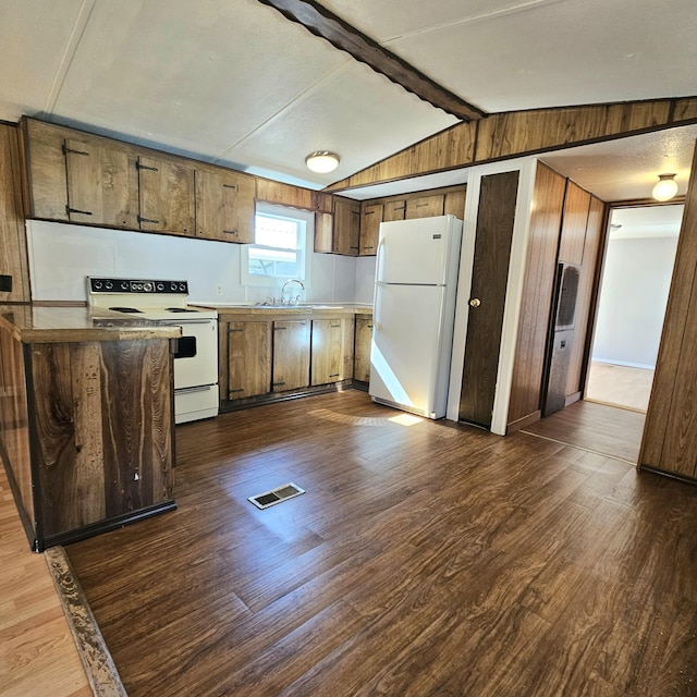 kitchen featuring white appliances, visible vents, dark wood finished floors, lofted ceiling with beams, and wood walls