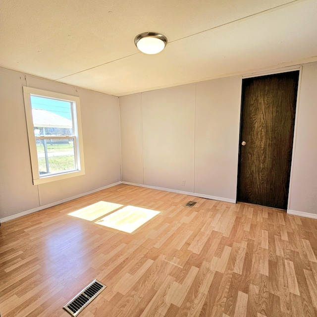 unfurnished room with visible vents, light wood-style flooring, and baseboards