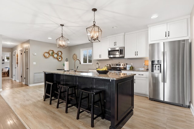 kitchen with a kitchen island with sink, white cabinets, appliances with stainless steel finishes, and a sink