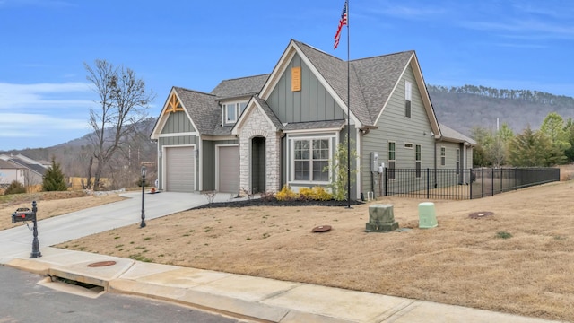 view of front facade with board and batten siding, fence, concrete driveway, a garage, and a mountain view