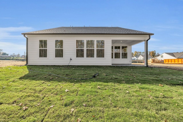 rear view of property with a lawn, fence, and roof with shingles