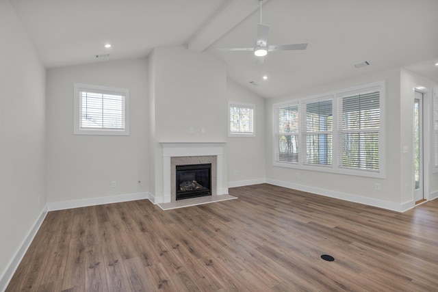 unfurnished living room with visible vents, baseboards, lofted ceiling with beams, wood finished floors, and a glass covered fireplace