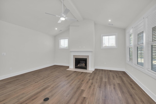 unfurnished living room with lofted ceiling with beams, plenty of natural light, wood finished floors, and a fireplace with flush hearth