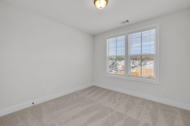 empty room featuring visible vents, baseboards, and light colored carpet