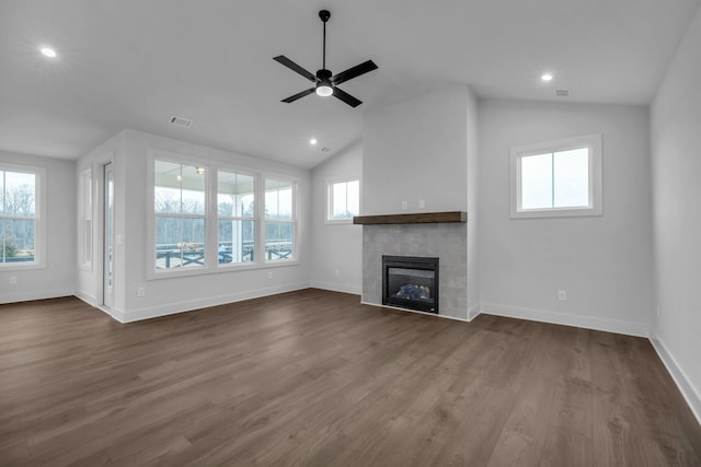 unfurnished living room with a wealth of natural light, visible vents, dark wood-style flooring, and a tiled fireplace