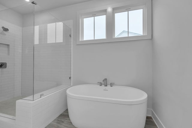 bathroom with a stall shower, baseboards, and a freestanding tub