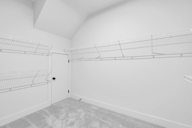 walk in closet with lofted ceiling and light colored carpet