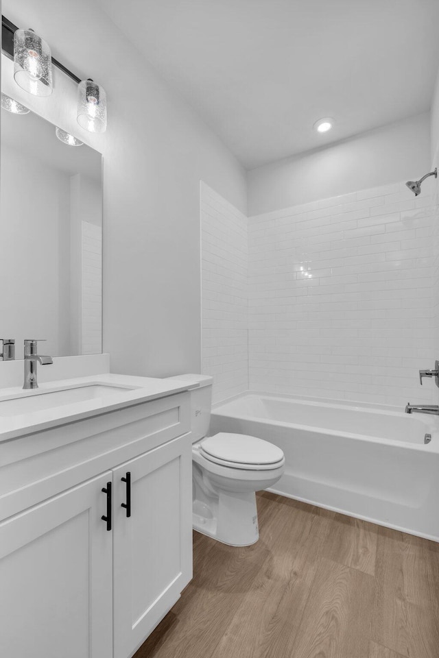 bathroom with toilet, vanity,  shower combination, and wood finished floors