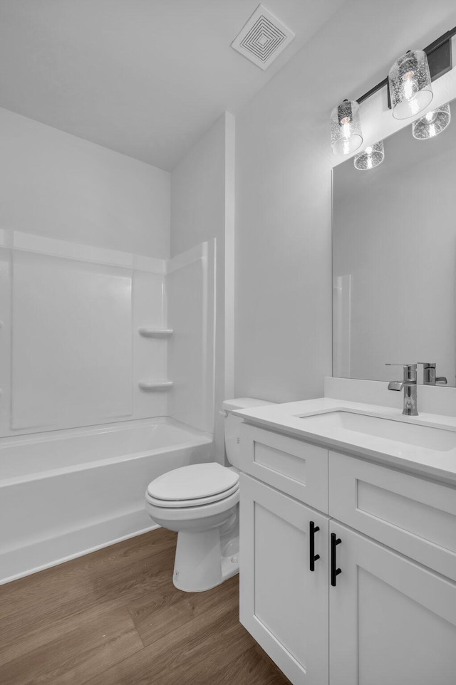 bathroom featuring visible vents, toilet, wood finished floors, bathtub / shower combination, and vanity