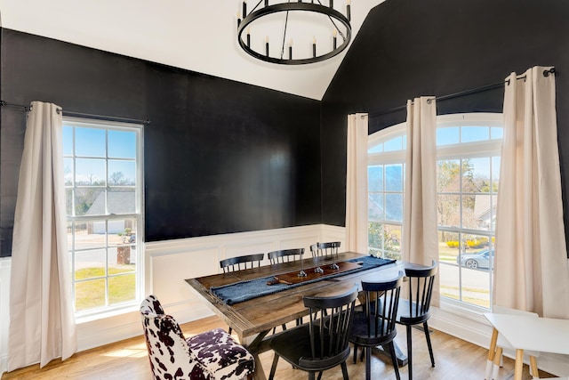 dining area with an inviting chandelier, a decorative wall, and light wood-type flooring