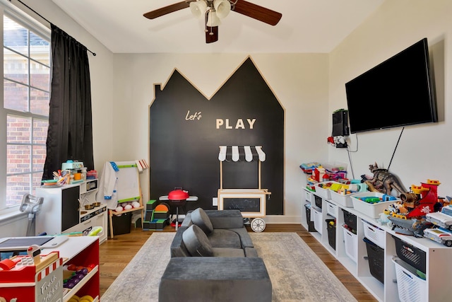 playroom featuring baseboards, a ceiling fan, and wood finished floors