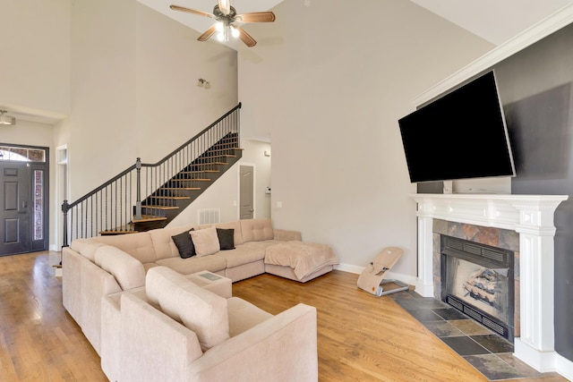 living area with visible vents, wood finished floors, stairway, a fireplace, and ceiling fan