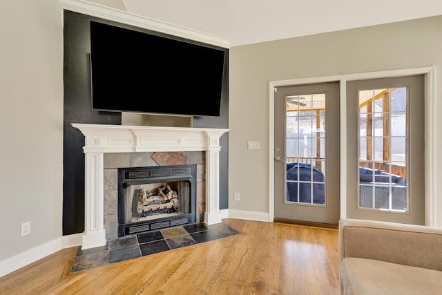 unfurnished living room featuring baseboards, wood finished floors, and a tiled fireplace