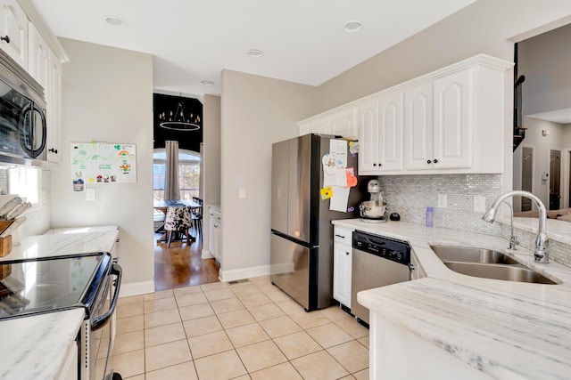 kitchen featuring light tile patterned floors, a sink, white cabinets, appliances with stainless steel finishes, and tasteful backsplash