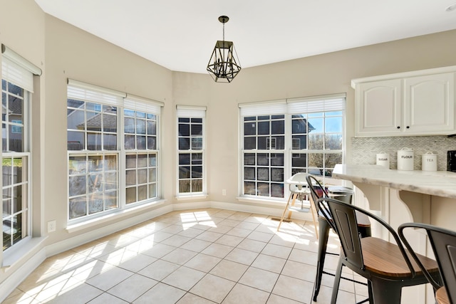 dining area with light tile patterned floors, a notable chandelier, and baseboards