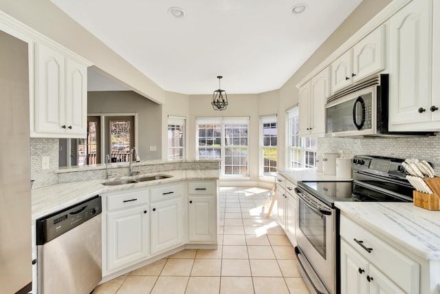 kitchen with a sink, white cabinetry, appliances with stainless steel finishes, light tile patterned flooring, and light stone countertops