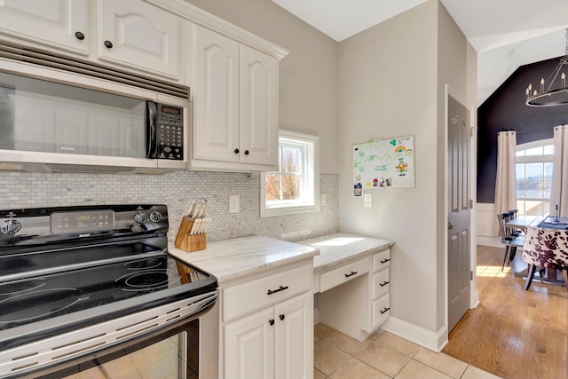 kitchen with light stone countertops, light tile patterned flooring, stainless steel appliances, decorative backsplash, and white cabinetry