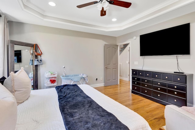 bedroom featuring visible vents, light wood-type flooring, a raised ceiling, and ornamental molding