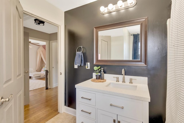 bathroom with baseboards, a ceiling fan, wood finished floors, and vanity