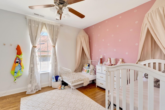 bedroom featuring visible vents, a ceiling fan, baseboards, and wood finished floors