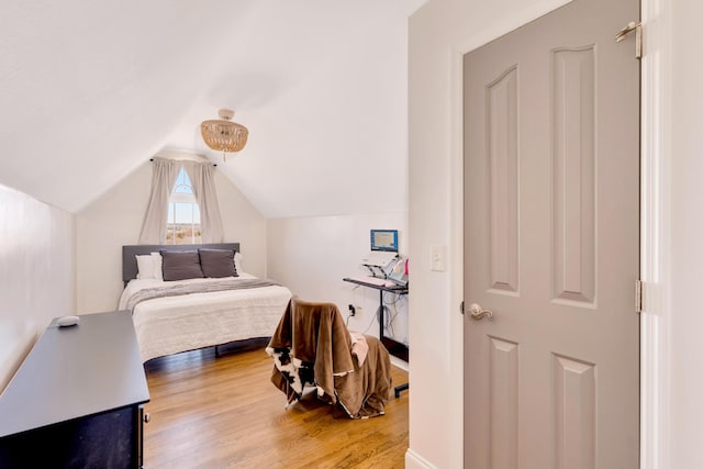 bedroom with vaulted ceiling and wood finished floors