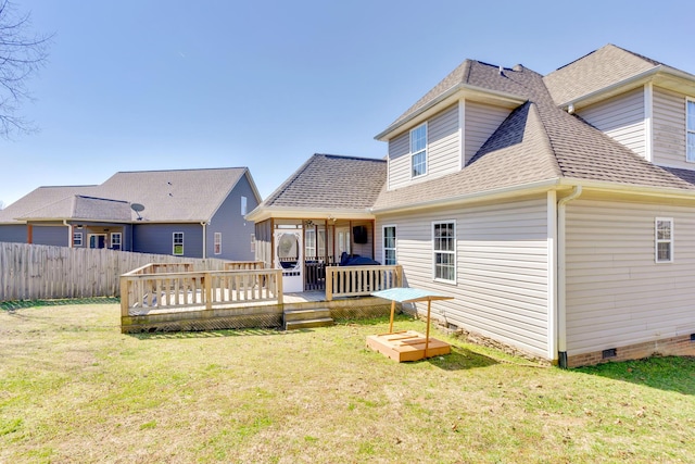 back of house with fence, roof with shingles, crawl space, a deck, and a lawn